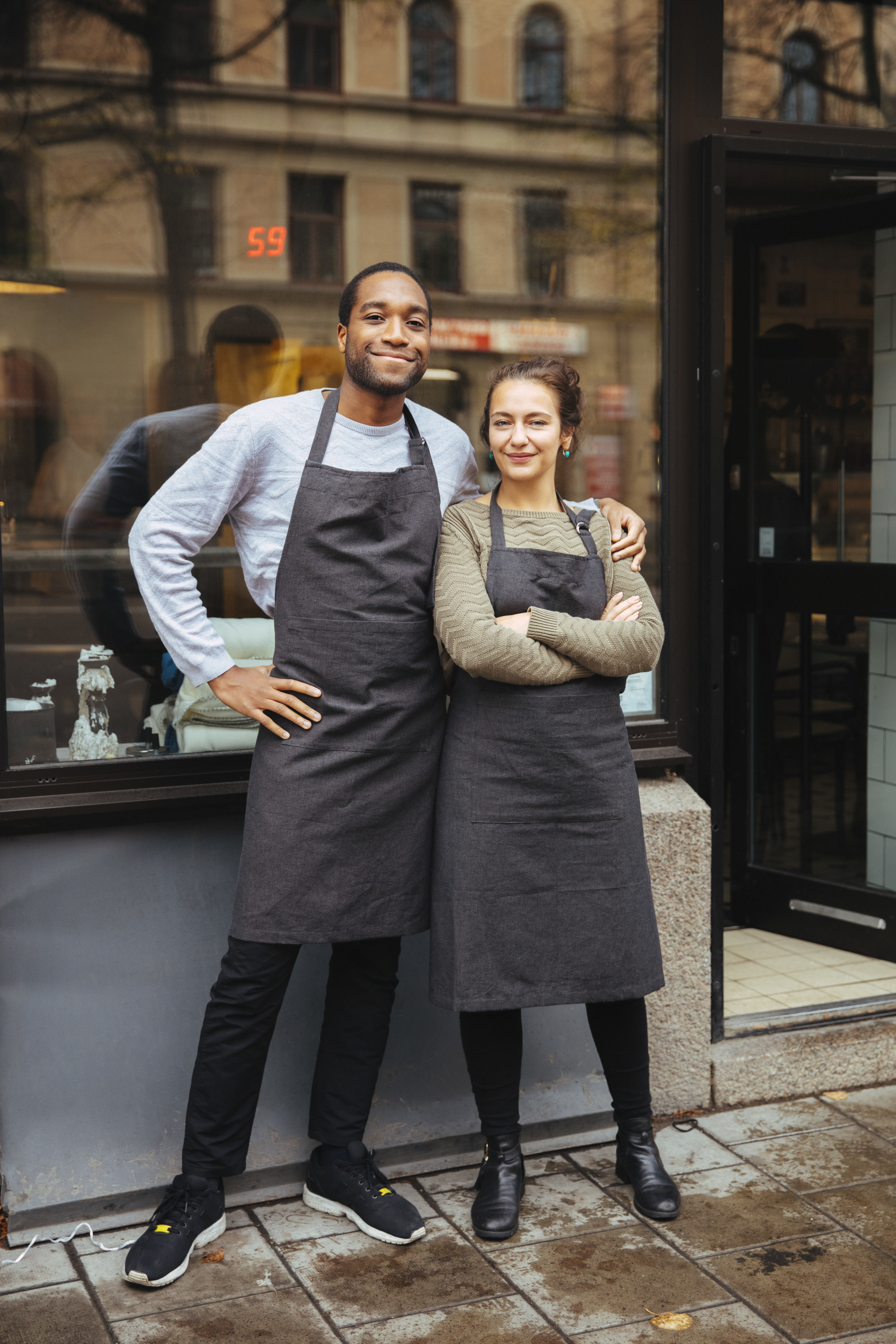 Man och kvinna står utanför ett café, håller om varandra och ler mot kameran